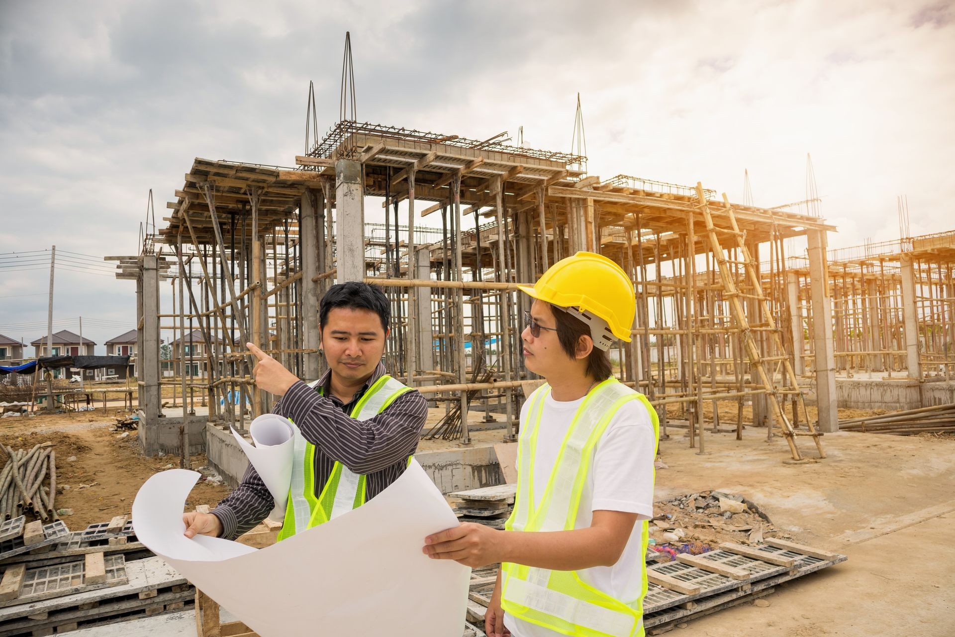 Asian business man construction manager and engineer worker in protective helmet hold blueprints paper on hand at house building site Asian business man construction manager and engineer worker in protective helmet hold blueprints paper on hand at house building site